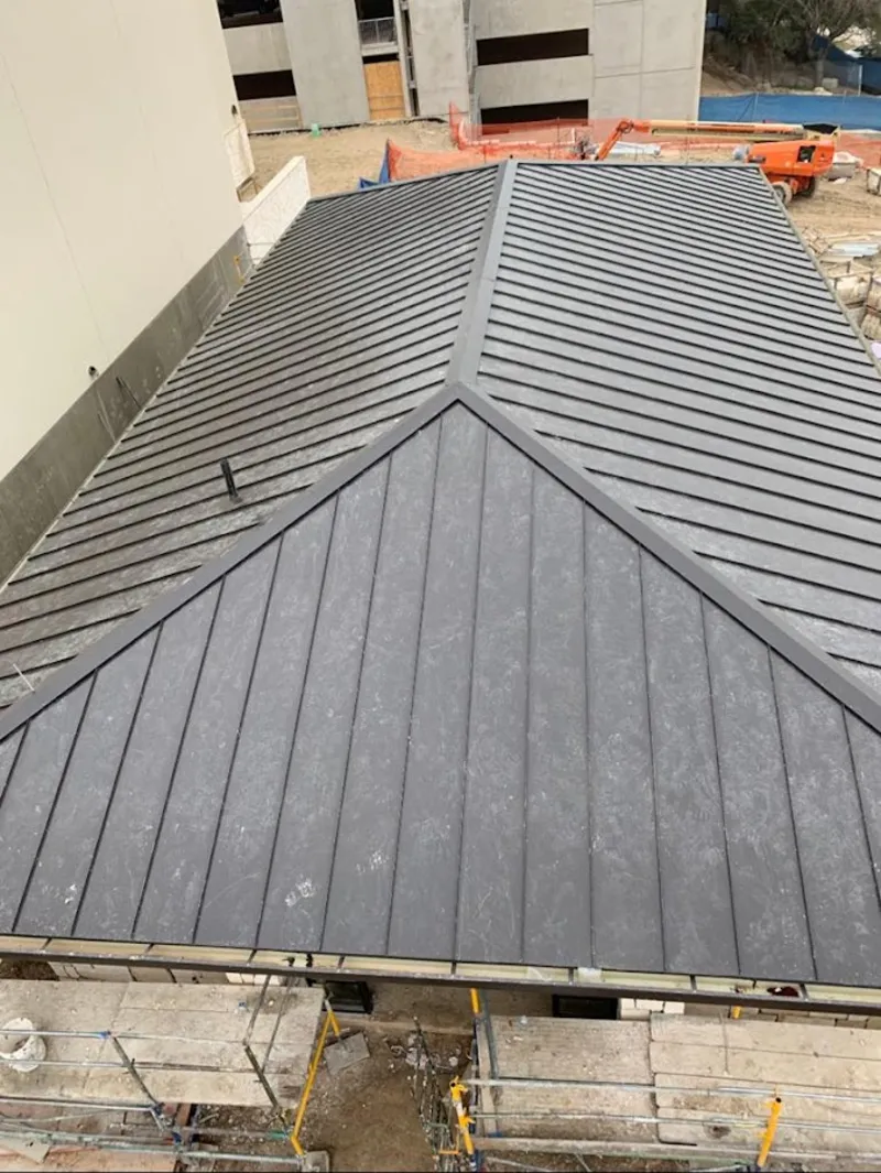 Commercial metal roof construction with crane equipment in Amherst